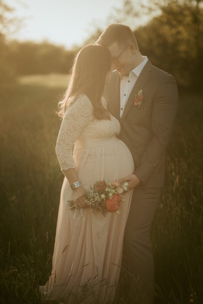 Schwangere Braut mit Bräutigam in der Abendsonne