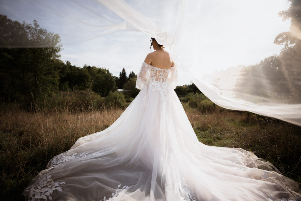 Braut von hinten mit langem Schleier, der nach oben weht