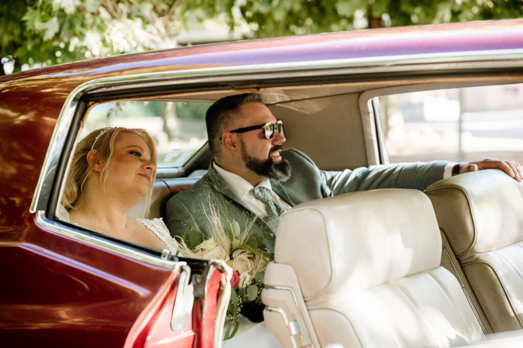 Brautpaar in einem Cadilac auf der Rückbank