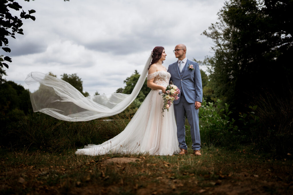Brautpaarportrait, der lange Schleier der Braut weht in der Luft