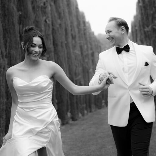 Brautpaar läuft zwischen einer Zypressenallee, Aufnahme mit leichter Bewegungsunschärfe