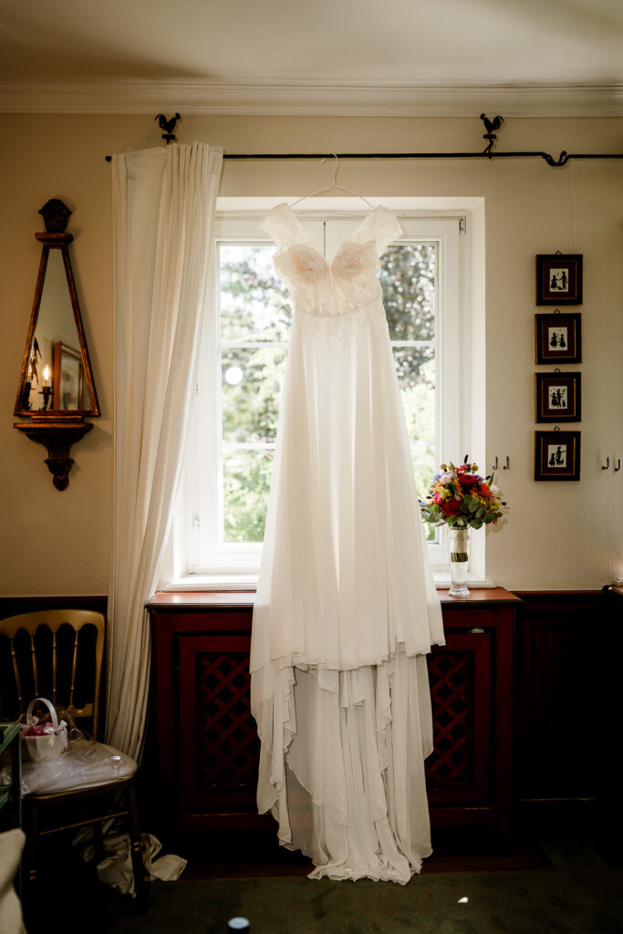 Brautkleid hängt vor Fenster im Styling Room, Detailaufnahme während des Getting Ready Saarland