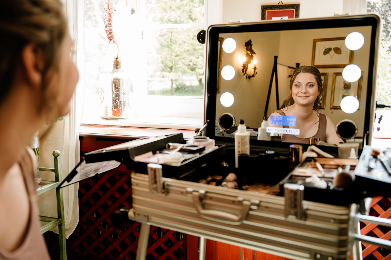 Braut nach dem schminken schaut sich im Spiegel an. Sie trägt noch kein Brautkleid.