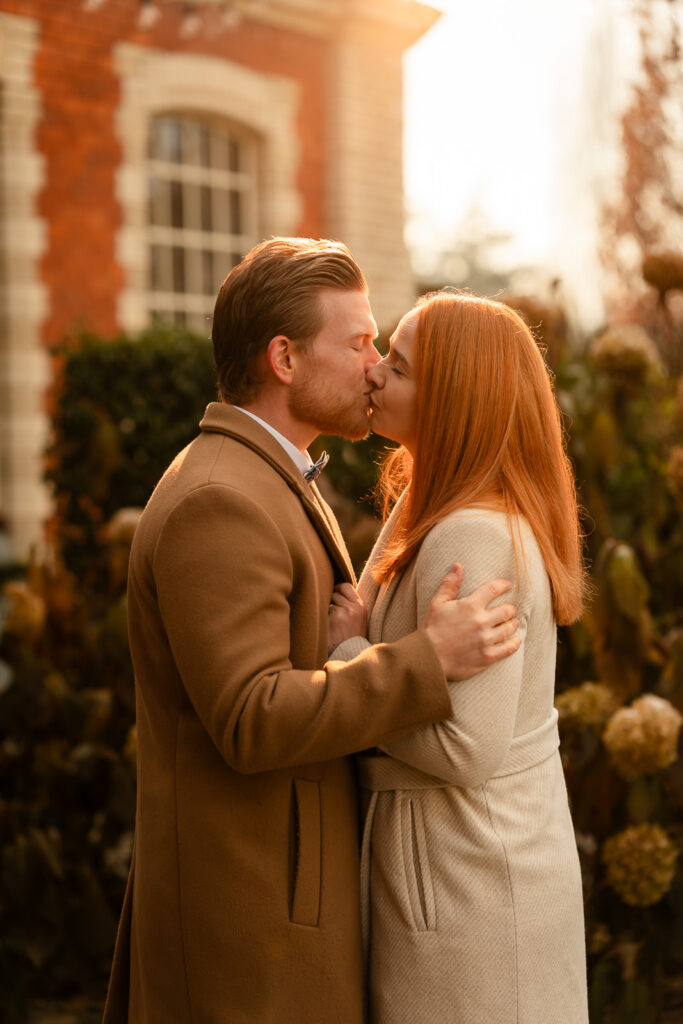 Brautpaar küsst sich vor einer alten Industriehalle im warmen Abendlicht
