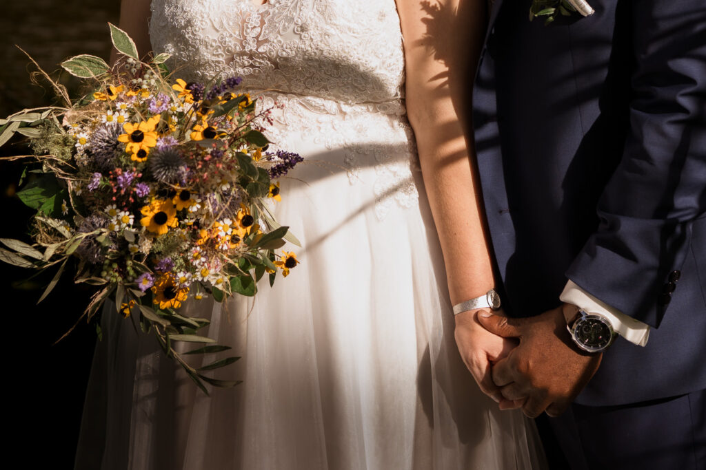 Detailaufnahme eines Brautpaares mit Schattenspiel einer Pflanze auf dem Brautkleid der Braut