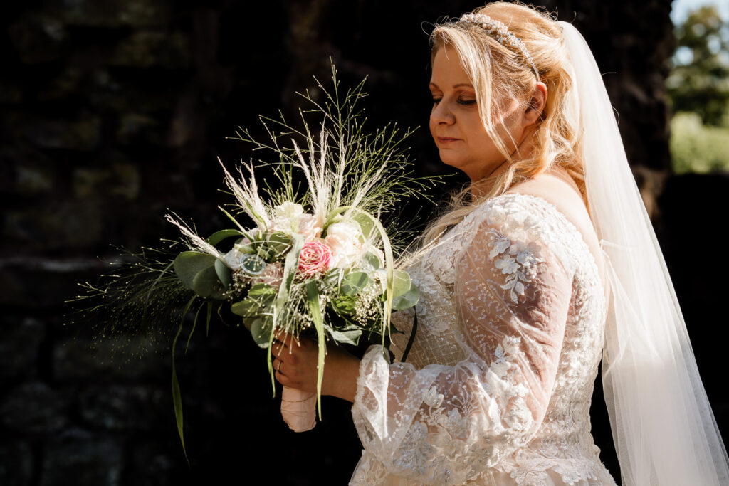 Braut schaut zu ihrem Brautstrauß