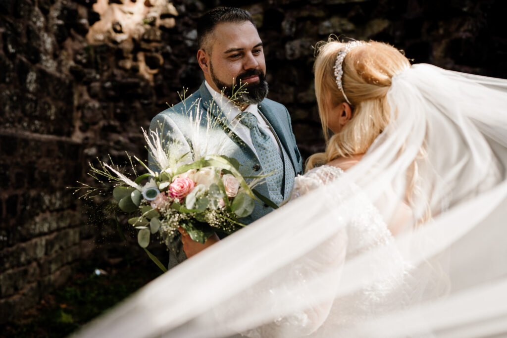 Brautpaar. Fotograf zeigt langen Schleier im Vordergrund