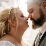 Nahaufnahme eines Brautpaares unter einem Schleier. Beide haben die Augen geschlossen