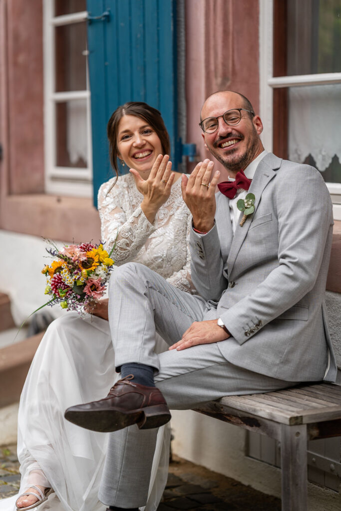 Brautpaar zeigt Hand mit Eheringen in die Kamera