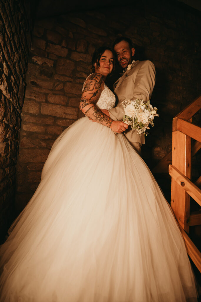 Weitwinkelaufnahme eines Brautpaares auf einer Treppe bei dem die Braut ein Prinzessinnenkleid trägt