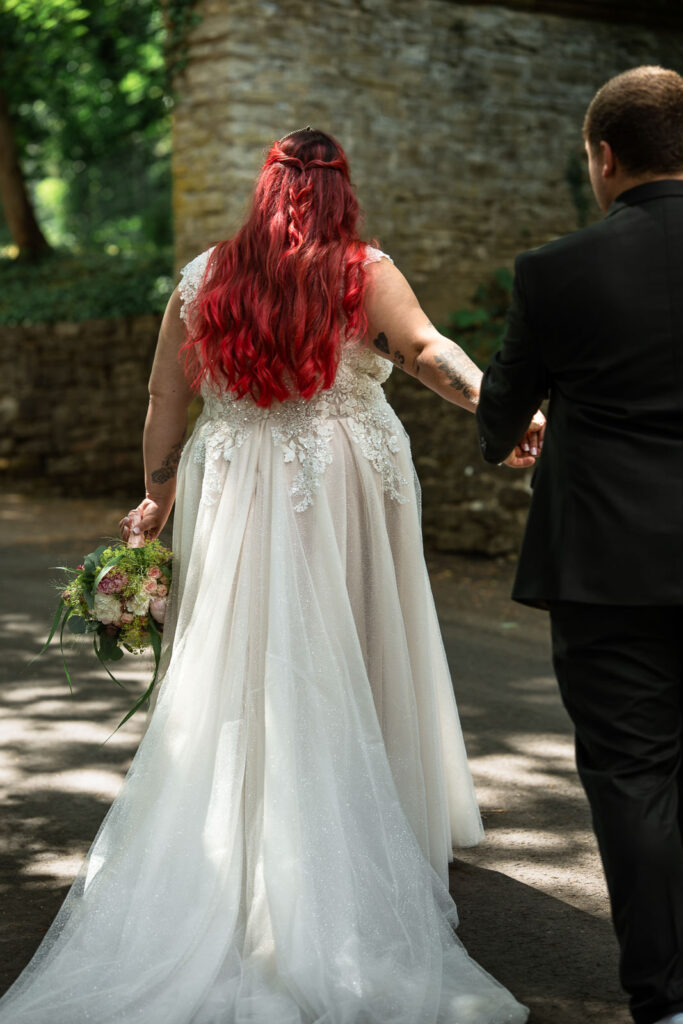 Rothaarige Braut geht vor und hat ihren Bräutigam an der Hand