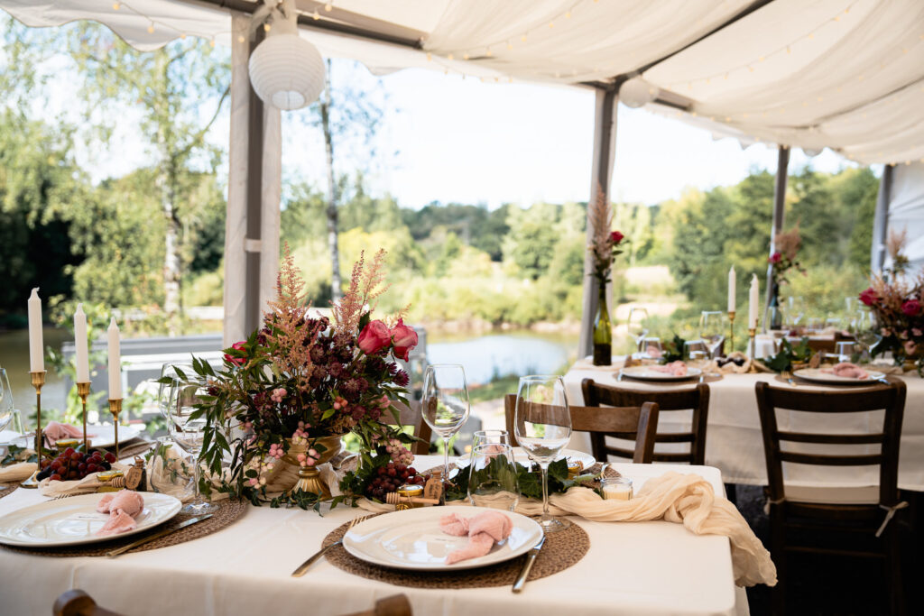 Dekoration der Gästetische in einem offenen Zelt an einem Weiher