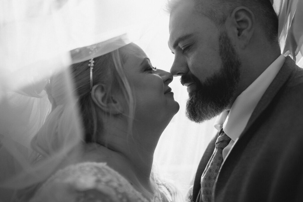 Brautpaar unter einem Schleier im Gegenlicht