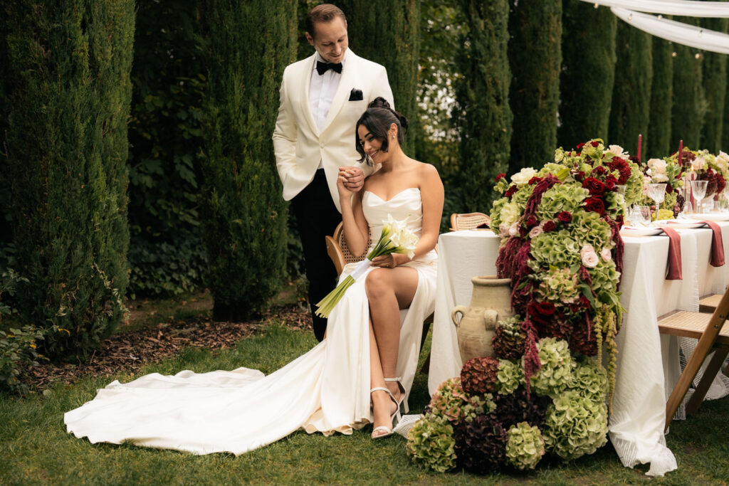 Braut sitzt auf einem Stuhl, Bräutigam steht dahinter