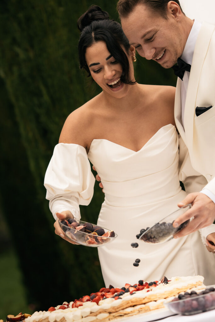 Brautpaar streut Obst auf einen Kuchen