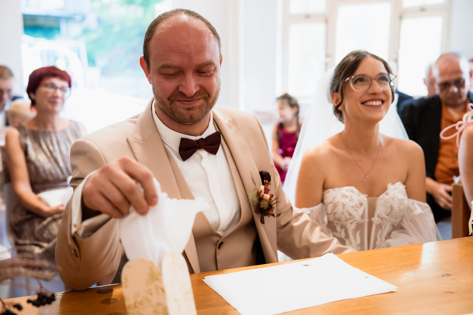 Bräutigam wischt sich bei der standesamtlichen Trauung Saarland eine Träne mit einem Taschentuch ab, im Hintergrund lächelt die Braut