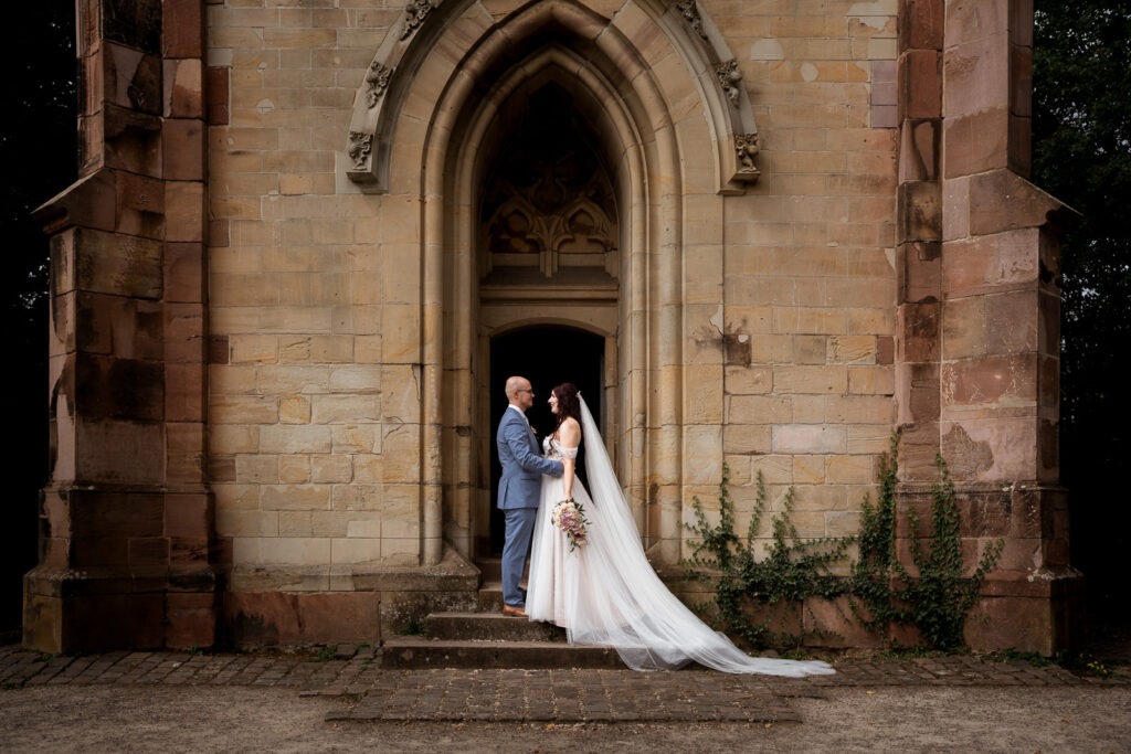 Brautpaar auf einer Treppe vor einer Kapelle