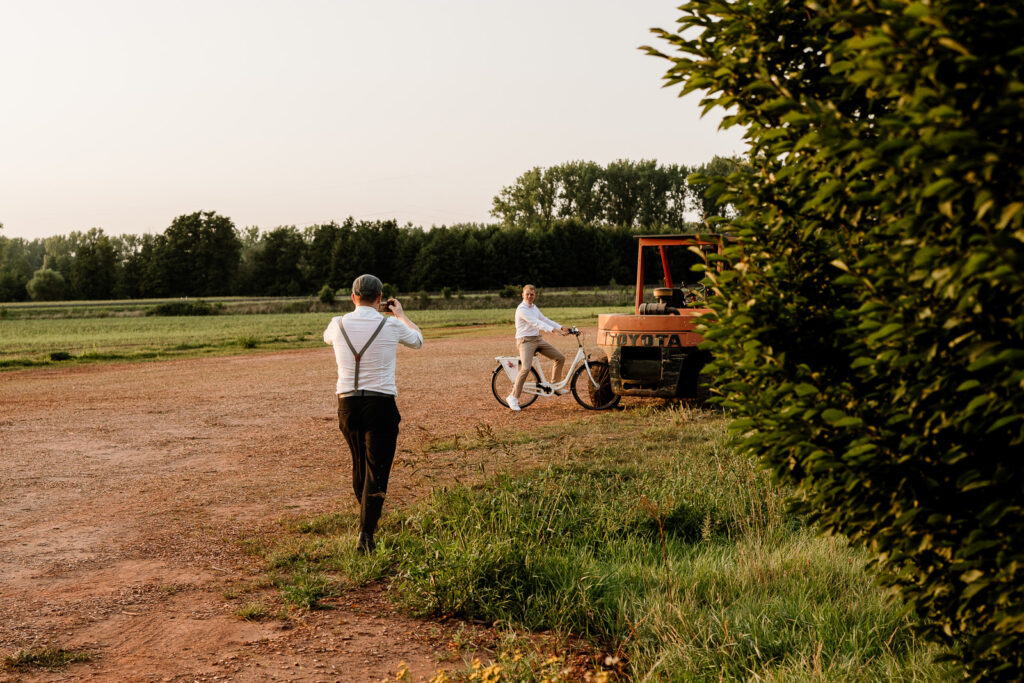 Mann fotografiert mit Handy einen Mann auf Fahrrad im Feld
