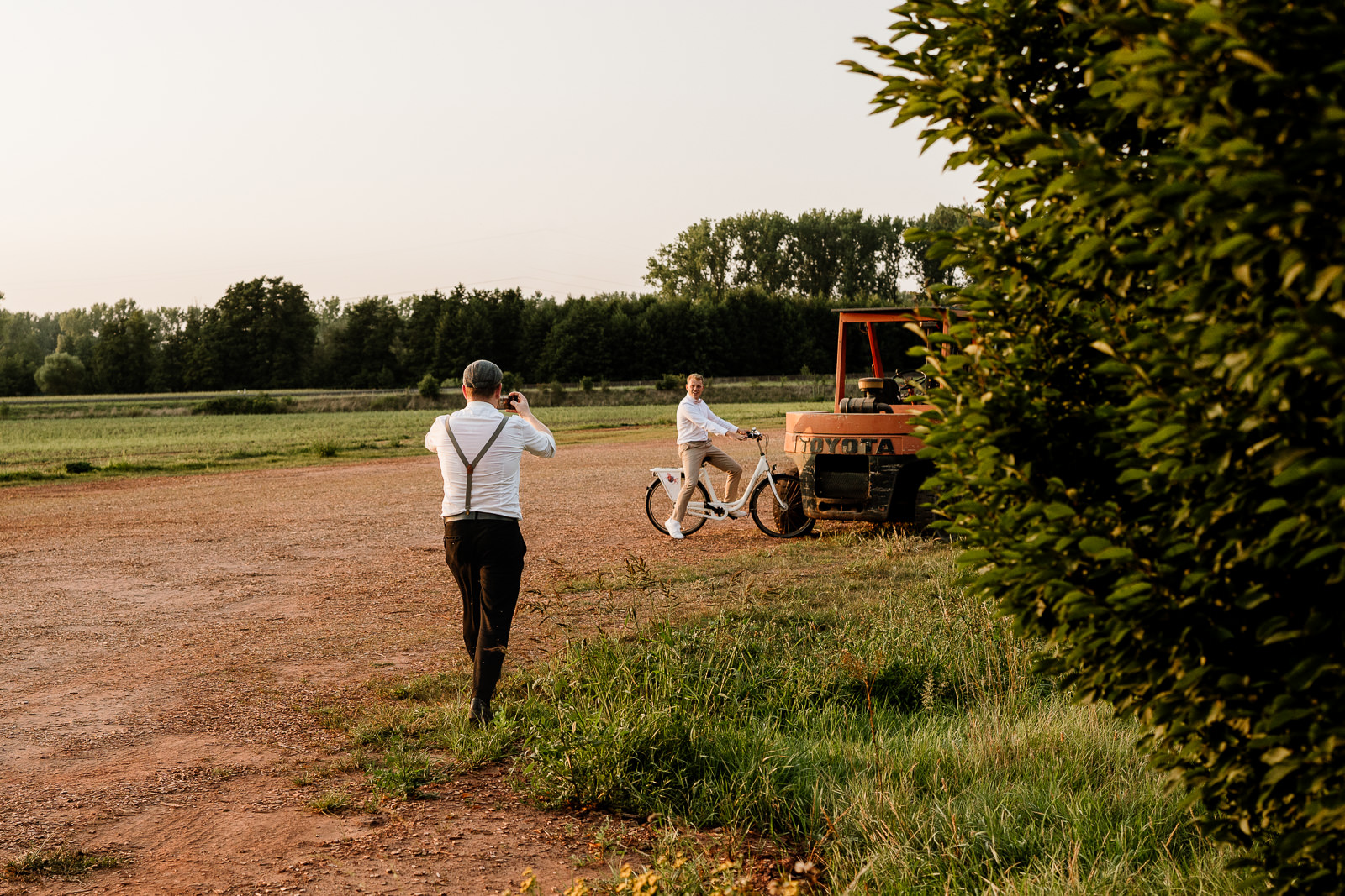 Mann fotografiert mit Handy einen Mann auf Fahrrad im Feld