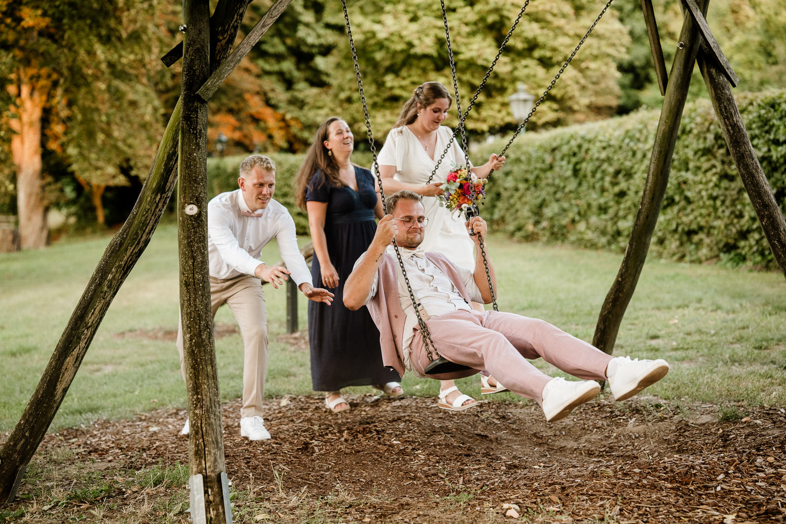 brautpaar auf schaukel wird von frau und mann angeschubst