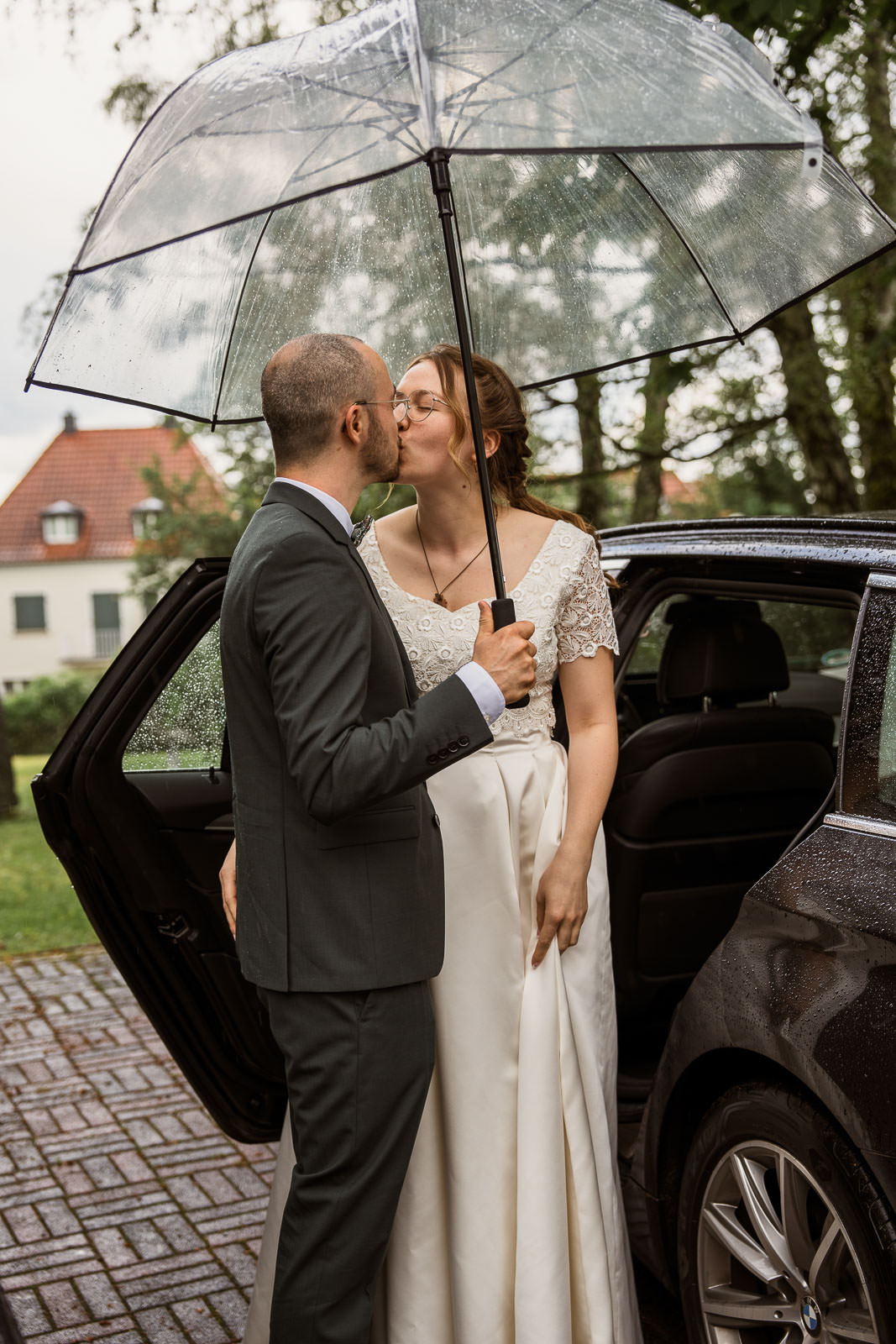 Regenhochzeit mit Brautpaar unter Schirm