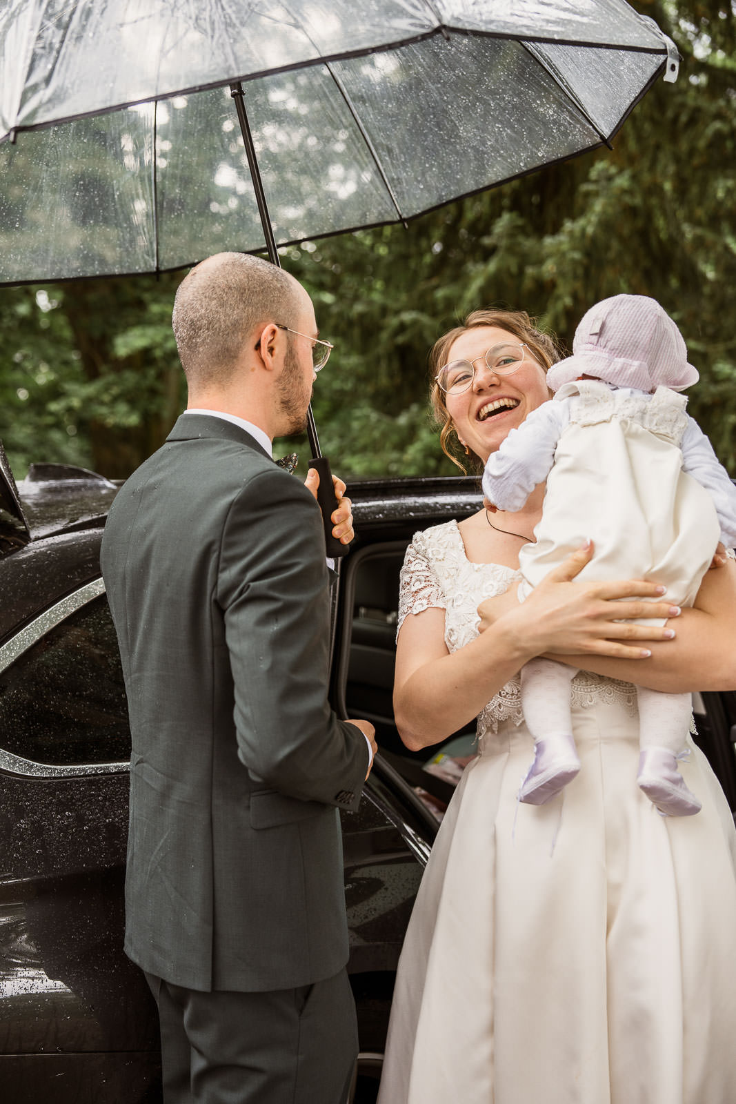 Hochzeit bei Regen mit Brautpaar vor Auto