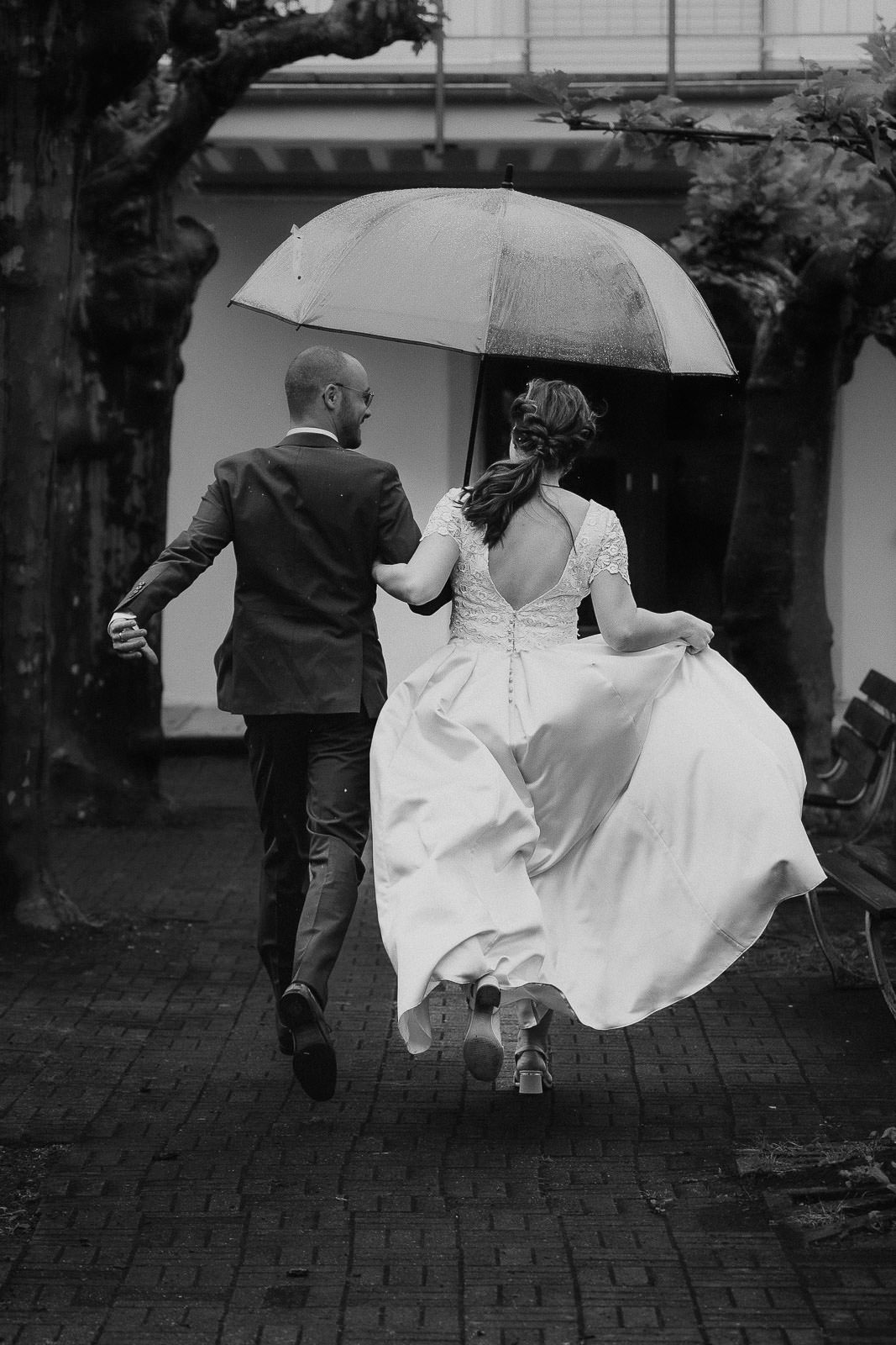Laufendes Brautpaar im Regen