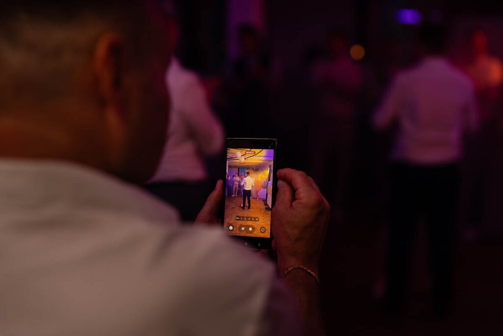 Jemand fotografiert mit Handy das tanzende Brautpaar. Handyaufnahme steht im Fokus