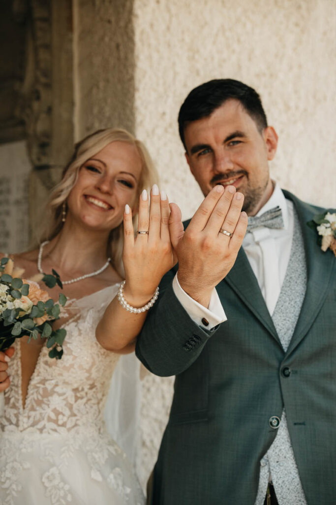 Brautpaar zeigt Ringe dem Hochzeitsfotograf